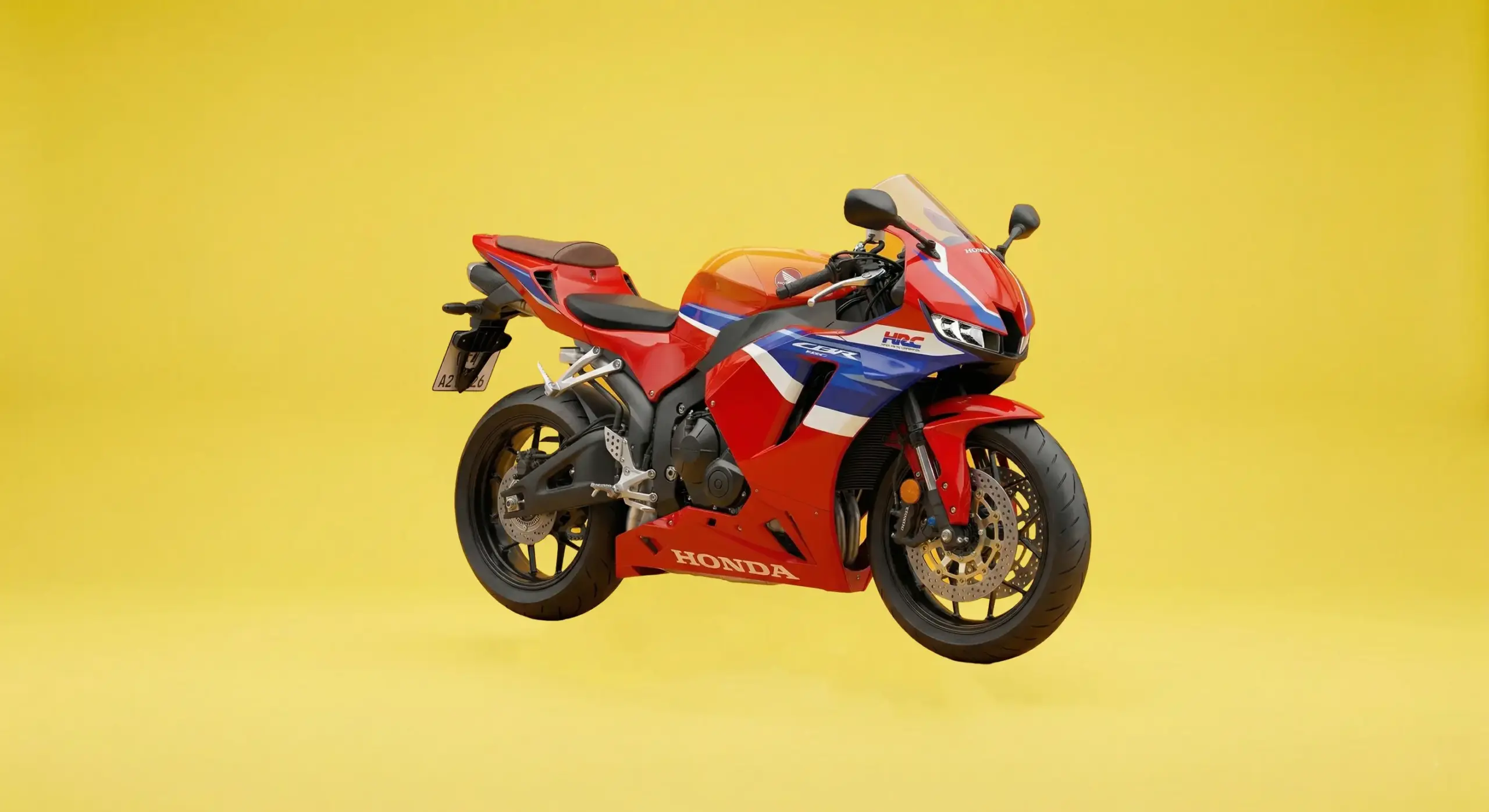 Nahaufnahme eines Honda CBR Sportmotorrads in den klassischen HRC-Rennfarben (Rot, Weiß, Blau) vor einem soliden, hellgelben Studiohintergrund in einer Front-Drei-Viertel-Ansicht.
